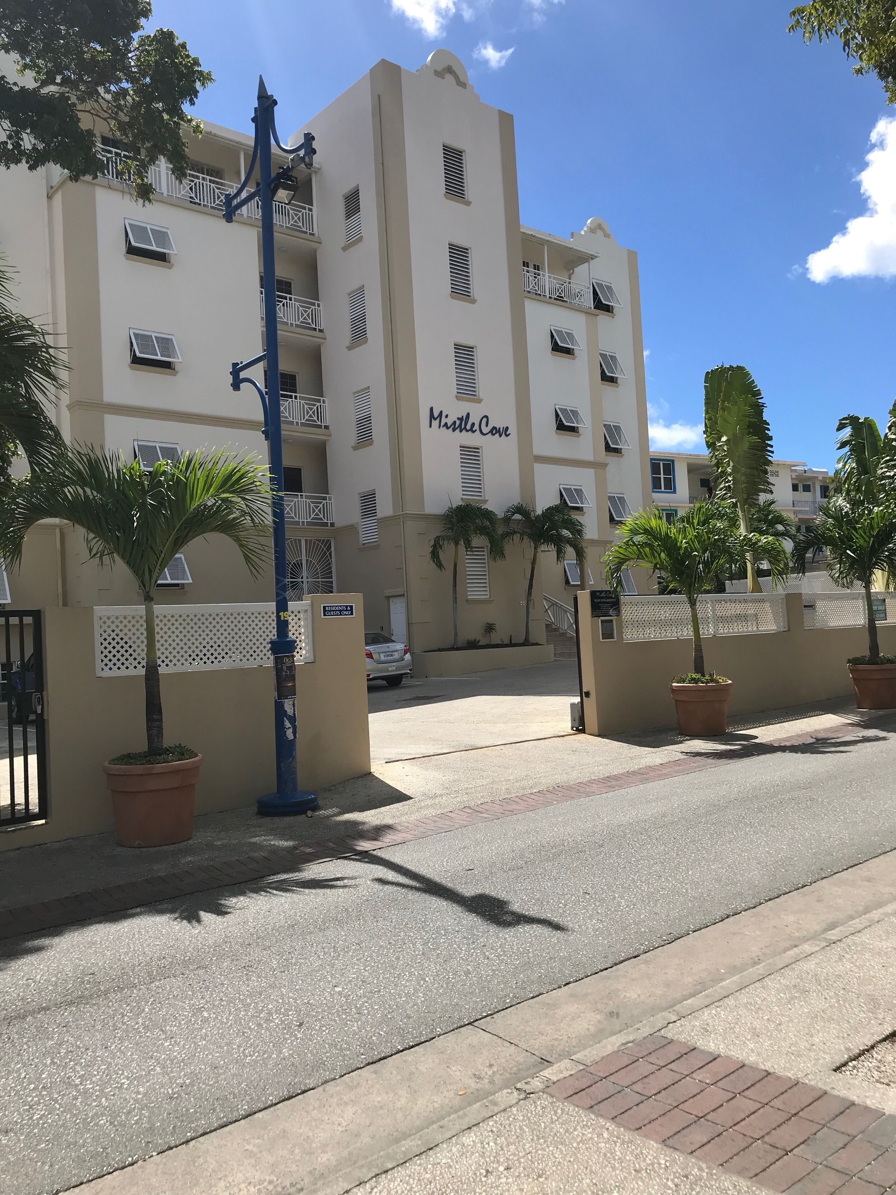 A multi-story building named "MistleCove" with balconies, air conditioning units, and a gated entrance.