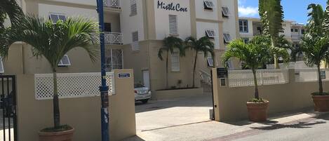 A multi-story building named "MistleCove" with balconies, air conditioning units, and a gated entrance.
