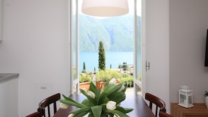 Ein Essbereich mit Blick auf einen See und Berge, ein Tisch mit Stühlen und einer hängenden Leuchte.