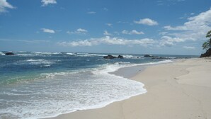 Une plage avec une eau d’un bleu limpide, des vagues et un rivage sablonneux.