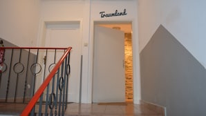 Een trap met een rode leuning die leidt naar een deur met de tekst 'Traumland'.