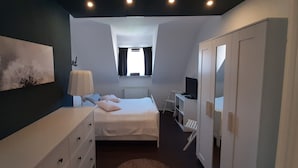 Een slaapkamer met een bed, een dressoir, een bureau en een kledingkast.