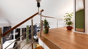 A modern interior with a wooden staircase, a dining area, and potted plants.