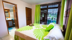 A bedroom with a bed, a bathroom, and a balcony with a table and chairs. - Pension Farehau (Faaa)