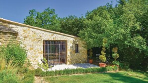 A stone building with a window and a door, surrounded by greenery and potted plants. - Luxurious home in Malaucene (Malaucene)