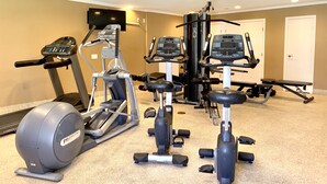 Ein Heimfitnessraum mit Laufband, Crosstrainer und Krafttrainingsgeräten.