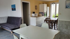 Un espacio habitable compacto con sofá, mesa de comedor y kitchenette.