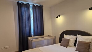 A bedroom with a bed, a headboard, a window with curtains, and a bedside table. - Cottage Bien-être Jacuzzi Piscine Chauffée Privée (Peyrole)