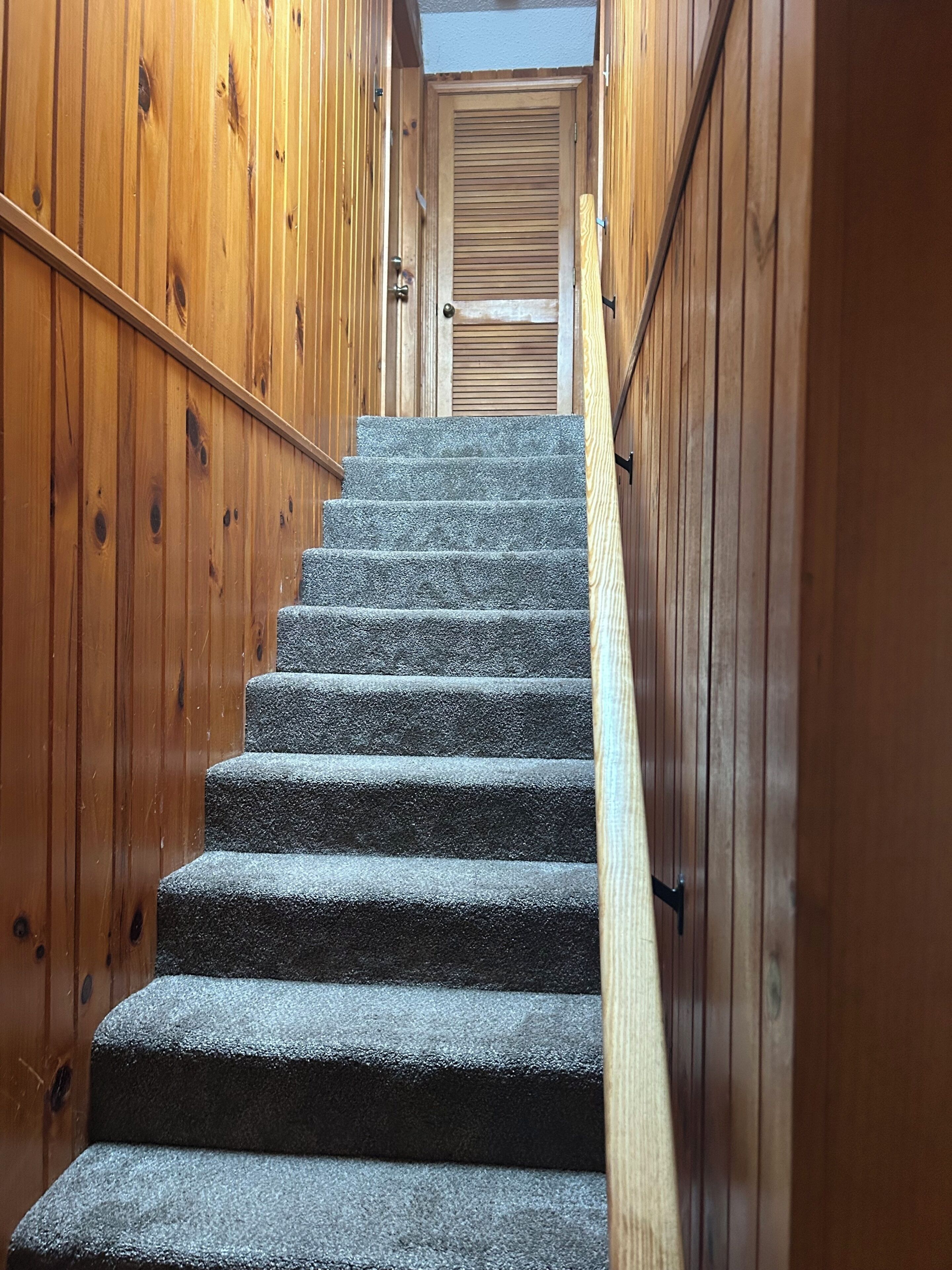 A wooden staircase with a handrail leading to a door at the top.