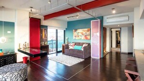 Un'ampia zona giorno con una parete decorata a rosso, un divano grigio e un tavolino da caffè in legno.