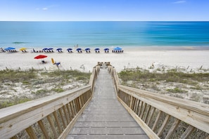 A wooden boardwalk leading to a beach with rows of beach chairs and umbrellas. - Stunning & Spacious 4BR Beachfront Condo at Adagio B202 with Gulf Front Views! (Santa Rosa Beach)