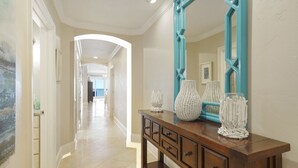 A hallway with a wooden console table, decorative vases, and a large mirror with a geometric frame. - Stunning & Spacious 4BR Beachfront Condo at Adagio B202 with Gulf Front Views! (Santa Rosa Beach)