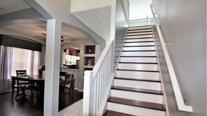 A staircase with wooden steps and white railings leading to an upper level. - Luxury 8 Bedroom Villa, Good for 18 to 20, Pool/Spa (Kissimmee)