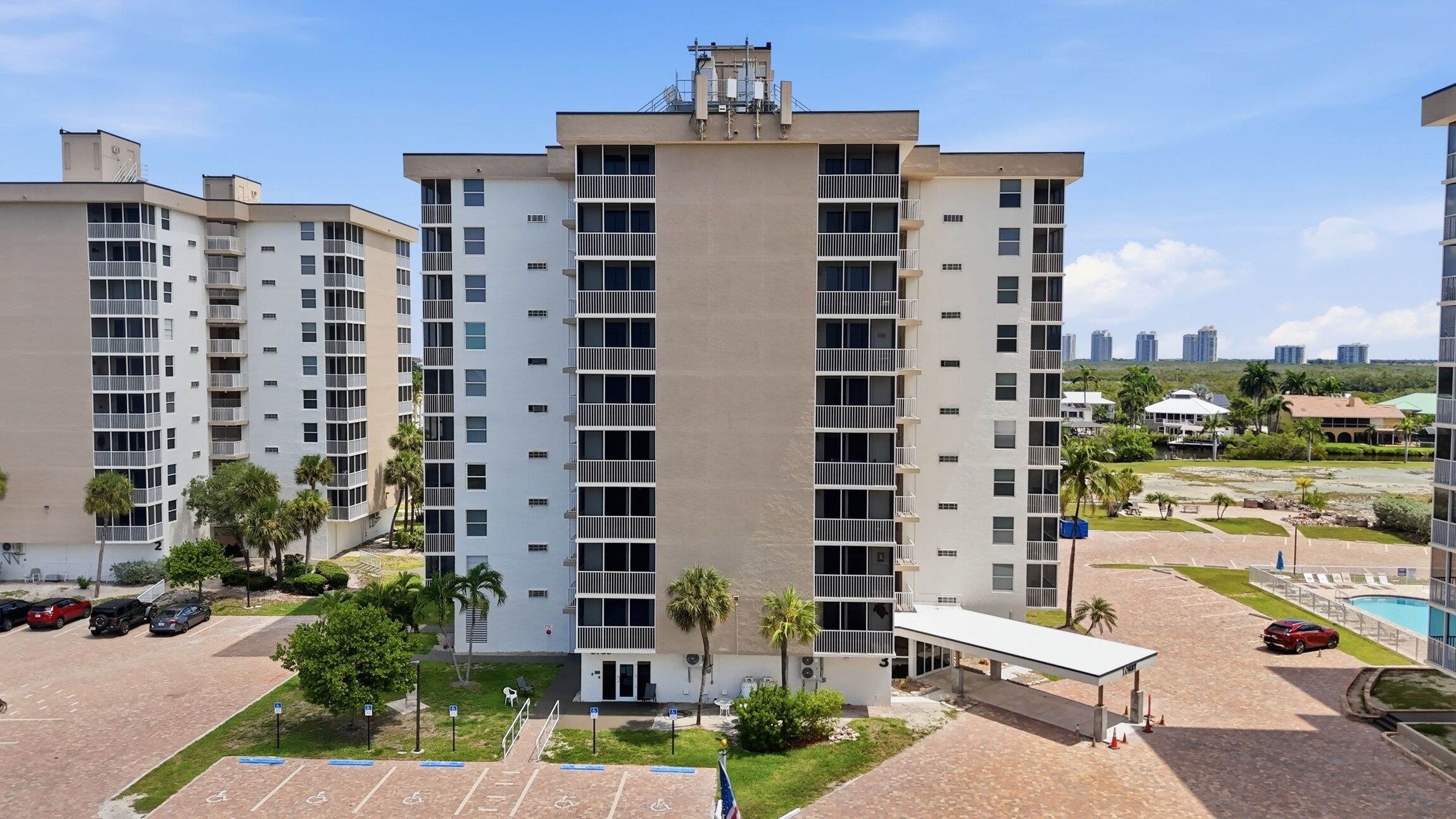 Un immeuble résidentiel à plusieurs étages, doté de balcons, d’un espace de stationnement et d’une piscine.