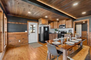Una cocina moderna con armarios de madera, una isla central y un comedor con mesa para cuatro.