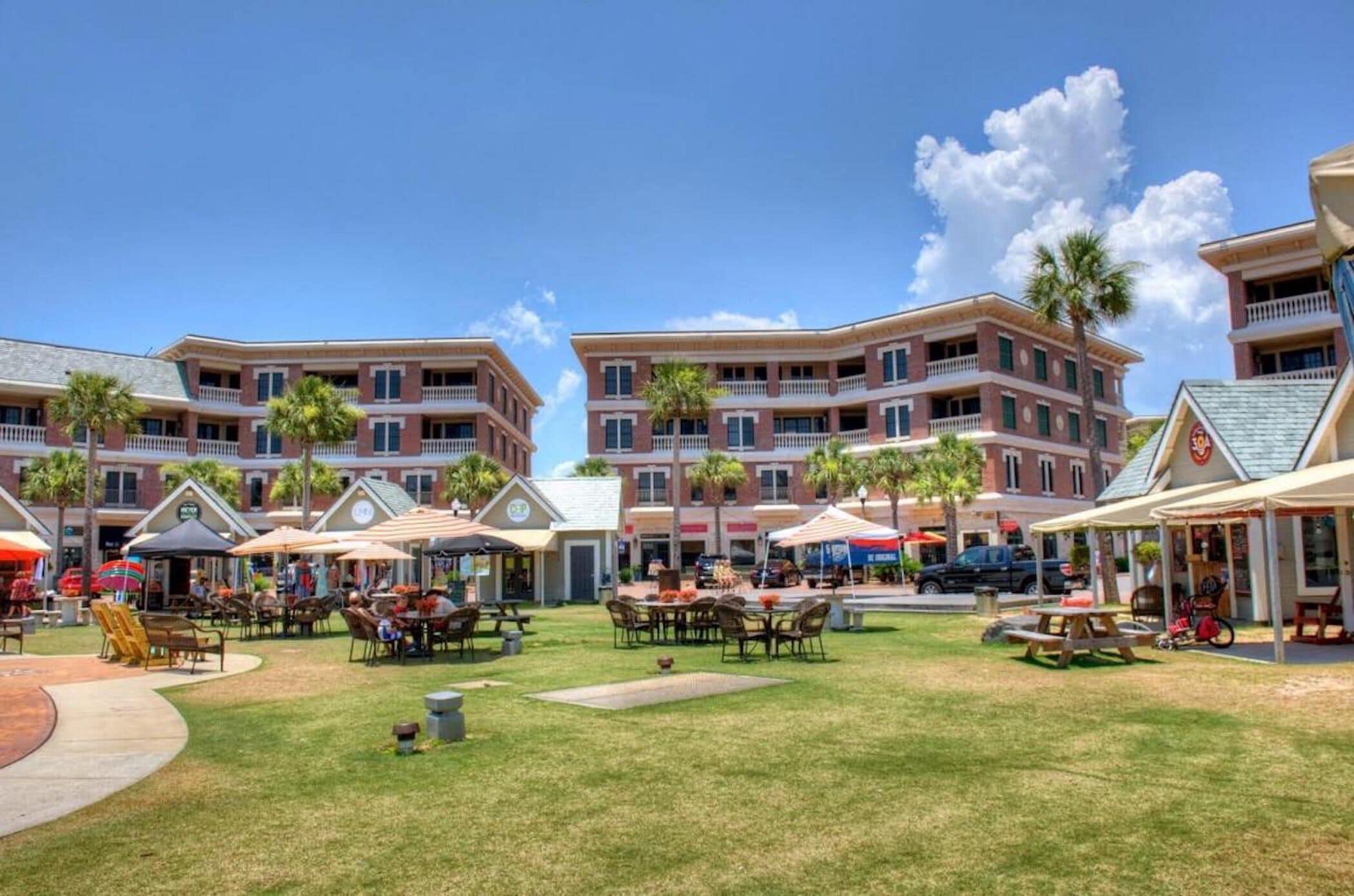 A courtyard with outdoor seating, palm trees, and a building with multiple balconies.