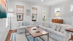 A living room with white walls, two white sofas, a wooden coffee table, and a floor lamp. - 5 BDRM & 6 seat golf cart! On the green, everything for KIDS, 2 King BDRMs (Santa Rosa Beach)