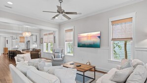 A spacious living room with a large sofa set, a wooden coffee table, and a television mounted on the wall. - 5 BDRM & 6 seat golf cart! On the green, everything for KIDS, 2 King BDRMs (Santa Rosa Beach)