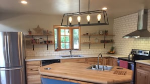 A modern kitchen with a central island, stainless steel appliances, wooden cabinets, and a window with a view. - Open, Airy Mountaintop Home (Carbondale)