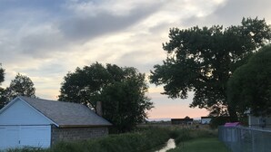 A narrow water channel flanked by grassy banks and trees, with a small white building on the left and a fence on the right. - Green River Mesa…your home away from home! (Green River)