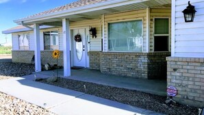 A single-story house with a covered porch, a front door with a wreath, and a security sign indicating 24-hour surveillance. - Green River Mesa…your home away from home! (Green River)