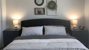 A bedroom with a bed, two bedside tables with lamps, a wall clock, and two framed pictures. - Green River Mesa…your home away from home! (Green River)