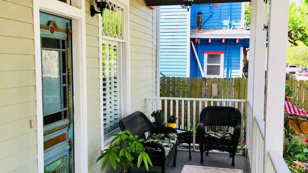 A porch with two wicker chairs, a green chair, and a potted plant. - Delightful, Relaxing, Restored Historic Apartment in Montrose section of Houston (Houston)