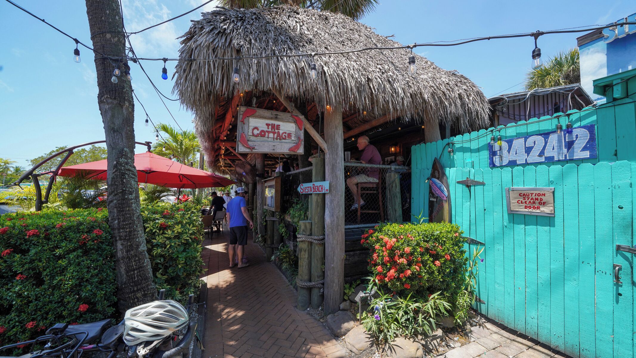 Un restaurant avec un toit de chaume, des tables en plein air et une enseigne indiquant « The Cottage ».