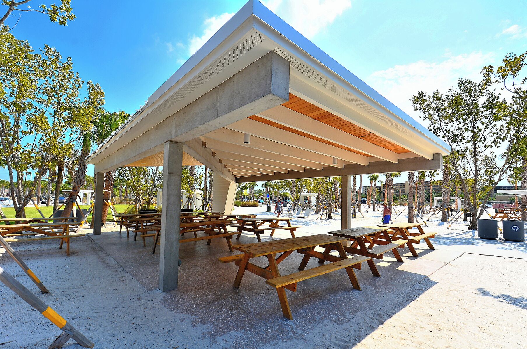 A covered picnic area with benches and tables, surrounded by trees.