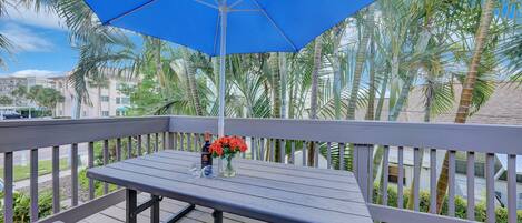 A wooden deck with a table and a blue umbrella.