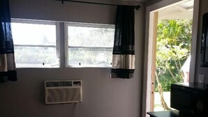 A room with a large window, an air conditioning unit, a desk with a computer, and a chair. - "Tiny Diggs" Is A Very Simple Lifestyle For One! (Jupiter)