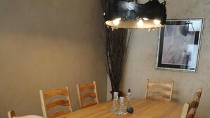 Ein Holzespeisesaal mit sechs Stühlen, einer Hängeleuchte und einer Vase mit Blumen auf dem Tisch.