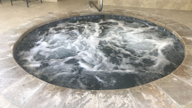 Ein Whirlpool mit Steinfassung und Metallgeländer.