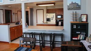 Una cocina con armarios de madera, una isla central con taburetes y un refrigerador.