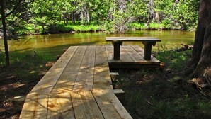 A wooden deck leading to a picnic table by a river.