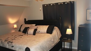 A neatly made bed with a headboard, a bedside table with a lamp, and a dresser against the wall.