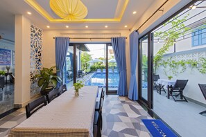 A hotel room with a pool view, a dining area with a table and chairs, and a reception desk.