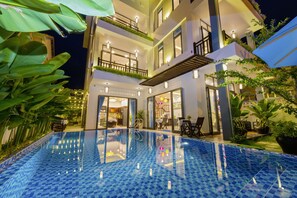 A modern hotel with a rooftop pool, outdoor dining area, and lush greenery. - Island Town Villas (Da Nang)
