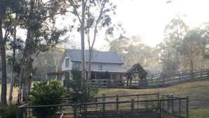 Ein Haus mit umzäunter Garten und einer Holzkonstruktion.