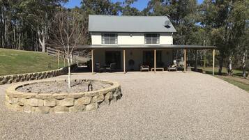 A house with a covered patio area, stone fire pit, and outdoor seating.