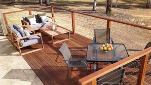 Eine Holzterrasse mit einer Couch, Stühlen und einem Tisch mit Obst.