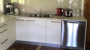 Eine moderne Küche mit einem Edelstahl-Geschirrspüler, einer Kaffeemaschine und einem Gewürzregal über der Spüle.