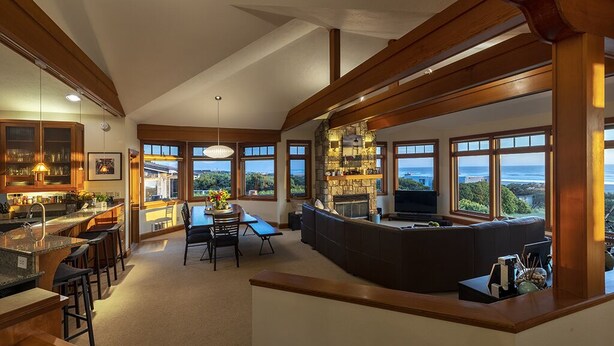 A spacious kitchen with a large island, dining area, and a fireplace. - DOGS, Panoramic Ocean Views, Game Room, EV Charger, New Hot Tub, Chef’s Kitchen (Waldport)