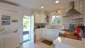 A modern kitchen with white cabinets, a microwave, a sink, and a red kettle.