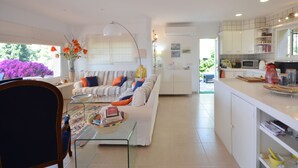 A modern living room with a sofa, coffee table, and a dining area with a chair and table.