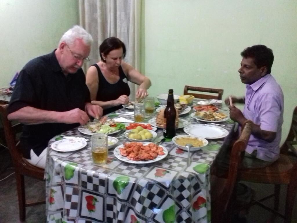 A dining table with various dishes and drinks, surrounded by chairs.