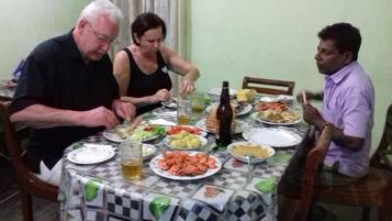 A dining table with various dishes and drinks, surrounded by chairs.