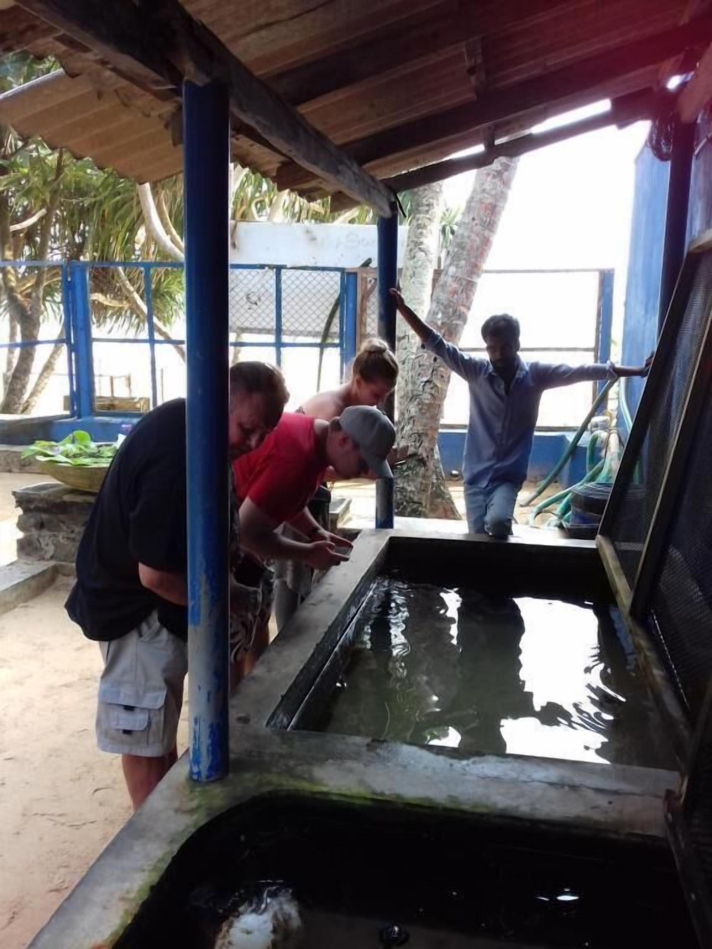 A group of people at a water pump under a shelter.
