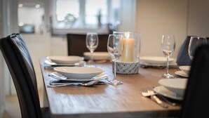 Una mesa de comedor dispuesta con platos, vasos y una vela en un ambiente moderno.