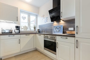 A modern kitchen with white cabinets, a built-in oven, and a coffee maker.